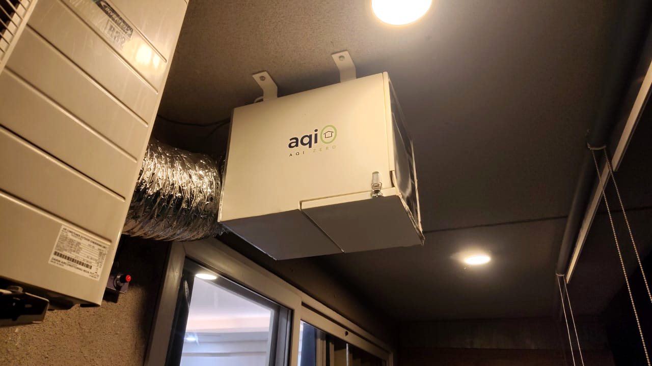 aqi0 unit mounted overhead on a balcony beside an air-conditioning condenser