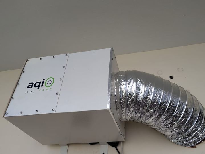 aqi0 unit on a wall under a balcony slab, its duct running into the wall