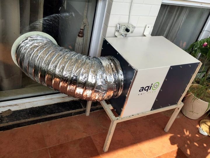 aqi0 unit on a floor stand on a terrace, its duct entering a glass door